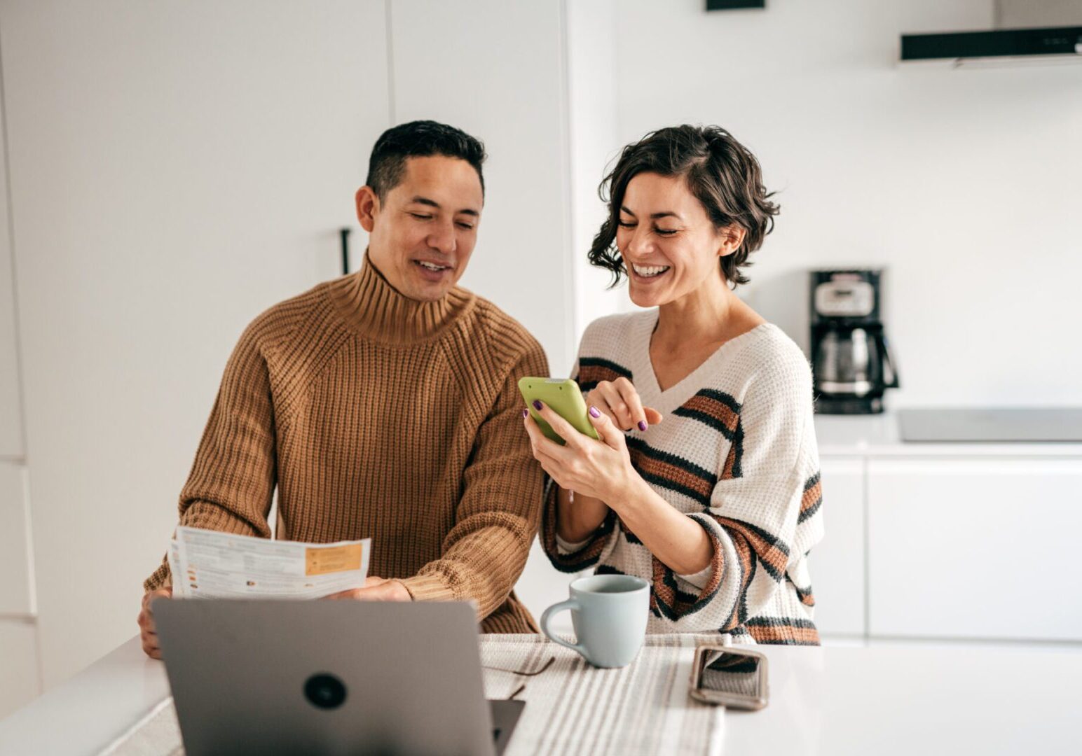 Smiling couple looking at phone in kitchen
