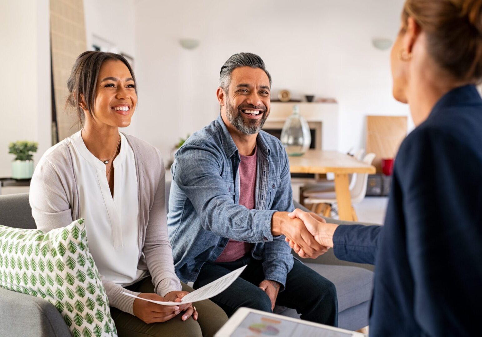 Smiling couple shaking hands with agent at home