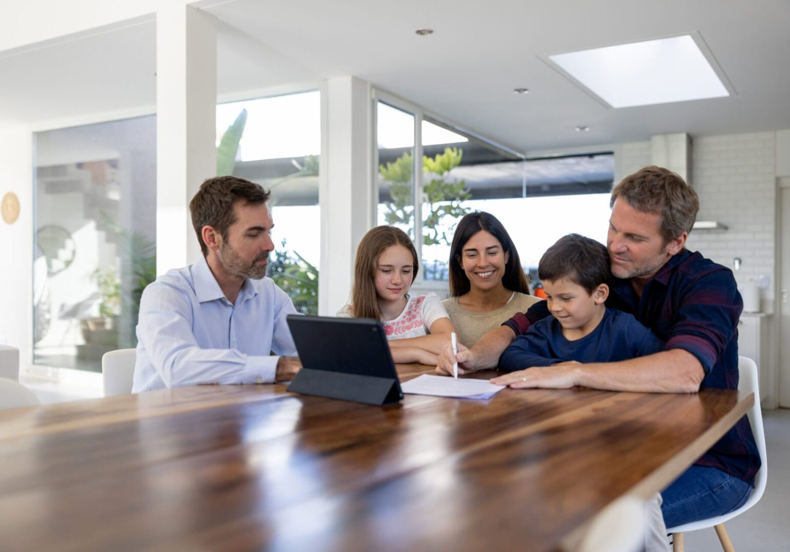 Family signing documents at kitchen table
